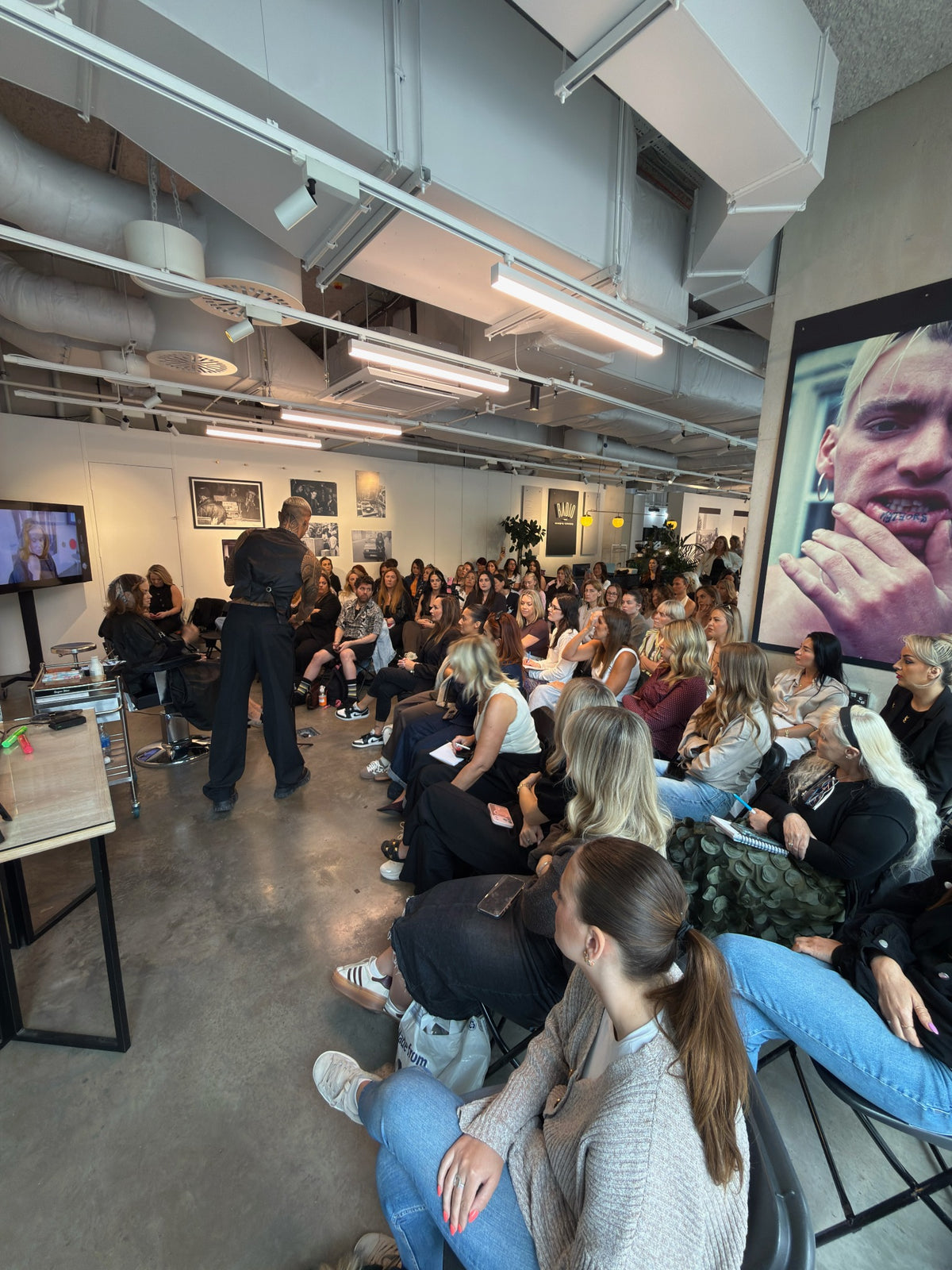 Kaine teaching a full room of hairdressers during a live education class